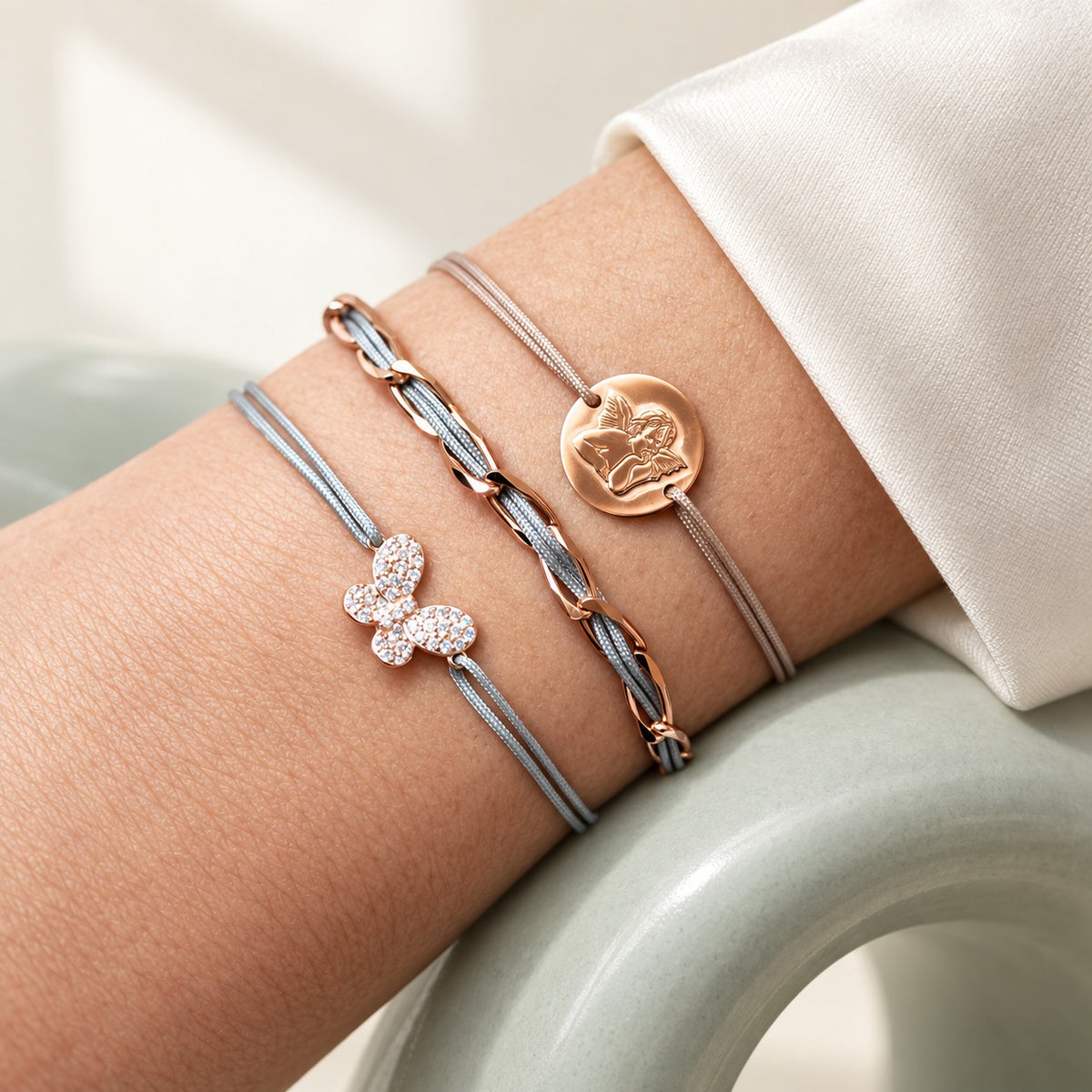 Armband Set mit 3 Armbändern am Handgelenk: Schmetterling Zirkonia, Unico hellgrau und Schutzengel aus 925 Sterling Silber rosé vergoldet